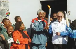  ??  ?? This file photo shows Former South African President Nelson Mandela (center) and former political prisoner Ahmed Kathrada (right) holding the Olympic Flame at the entrance to the former maximum security prison on Robben Island, Cape Town. Celebrated...