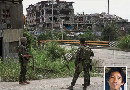  ?? — Reuters ?? Tense situation: Soldiers standing guard inside the war-torn area in Marawi City where Amin Baco (inset) is hiding with 30 IS militants in a mosque.