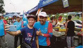  ?? SYARAFIQ ABD SAMAD PIC BY ?? PKR candidate Mohd Zawawi Ahmad Mughni (right) on a walkabout at Pasar Tani Sri Andalas in Klang yesterday.