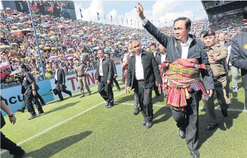  ?? WICHAN CHAROENKIA­TPAKUL ?? Gen Prayut Chan-o-cha, with a ‘pha khao ma’ wrapped around his waist, waves to a crowd at Chang Arena Stadium in Buri Ram during his visit.