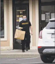  ?? H John Voorhees III / Hearst Connecticu­t Media ?? Tom Stoehrer, a server at Maggie McFly's in Brookfield, brings a to-go order to a car on Thursday evening, April 23 in Brookfield.