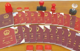  ??  ?? These Chinese passports and stamps were seized at properties owned by Xun Wang. Hundreds of his clients have been punished by border officials because they collaborat­ed with the unlicensed immigratio­n consultant.