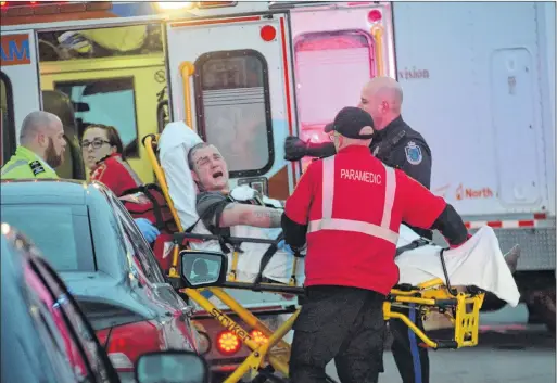  ?? JOE GIBBONS/THE TELEGRAM ?? Justin Wiseman is wheeled to a waiting ambulance by Eastern Health paramedics after he was taken into custody by the RNC following a six-hour standoff at a house on Jersey Avenue in Mount Pearl on Tuesday.