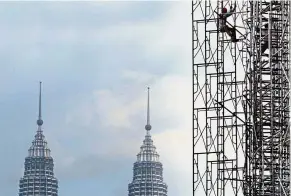  ??  ?? Cash reserves: A worker is seen at a constructi­on site, with the Petronas Twin Towers in the background. According to Moody’s, Petronas’ net cash position was RM97bil as at end-June 2018.