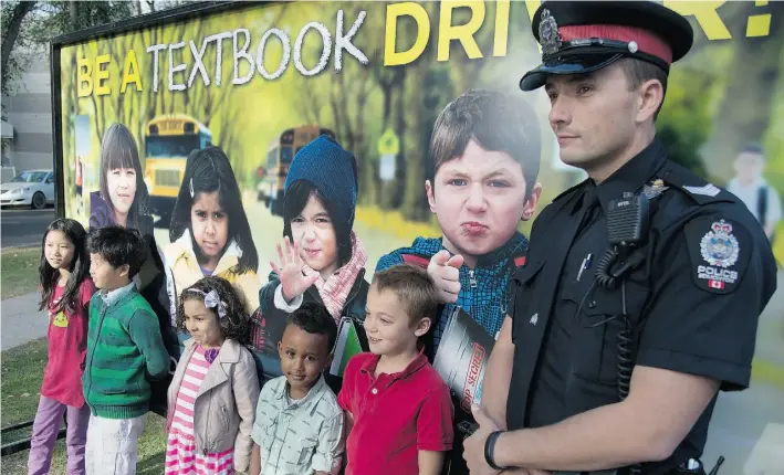  ?? BRUCE EDWARDS/ EDMONTON JOURNAL ?? Sgt. David Green with children from Mother Teresa Catholic School as Edmonton Police Service launches the second year of its Textbook Driver public awareness campaign.