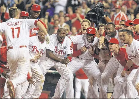  ??  ?? The Phillies’ Reid Brignac is about to be mobbed by teammates after his walk-off three-run homer in the ninth inning against the San Diego Padres at Citizens Bank Park in Philadelph­ia. The Phillies won 3-0.
