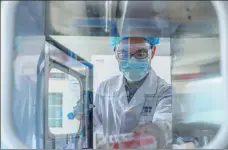  ?? XINHUA ?? An employee handles trial vaccine samples at a COVID-19 vaccine production base of Sinopharm in Beijing.