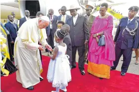  ??  ?? Pope Francis is welcomed by Uganda’s president, Yoweri Museveni, center with hat, at Entebbe Internatio­nal Airport on Friday.