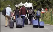  ?? CHARLES KRUPA — THE ASSOCIATED PRESS ?? A family from Haiti approach a tent in Saint-Bernard-deLacolle, Quebec, stationed by Royal Canadian Mounted Police, as they haul their luggage down Roxham Road in Champlain, N.Y., Monday. Officials on both sides of the border first began to notice last...