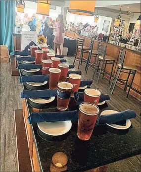  ?? John Dehler / For Hearst Media Connecticu­t ?? Amid the table settings at Guilford Mooring Restaurant, poured pints of Thimble American Ale and an American flag folded for burial, was a sign that read, “Reserved for our Fallen Heroes.”