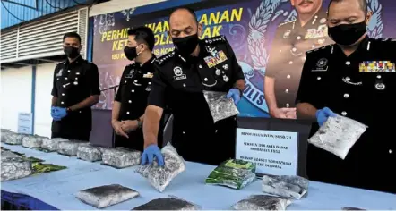  ?? ?? Drug haul: Comm mior Faridalath­rash (second from right) arranging packets of seized syabu in Ipoh.