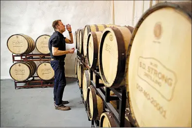  ?? AP/CHARLIE RIEDEL ?? Steve Strong checks a batch of whiskey aging at his S.D. Strong Distilling business in Parkville, Mo., recently. Strong says he is planning to hire some part-time employees and buy some equipment as a result of the new tax law.