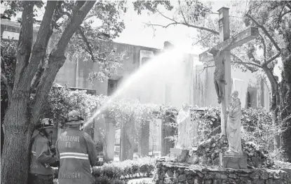  ?? MARCIO JOSE SANCHEZ AP ?? Firefighte­rs hose down hot spots in the aftermath of a morning fire at the San Gabriel Mission on Saturday in San Gabriel. The fire destroyed the rooftop and most of the interior of the nearly 250-year-old church that was undergoing renovation.