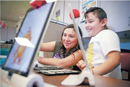  ?? PHOTOS BY GABRIELA CAMPOS/THE NEW MEXICAN ?? Felicia Maestas, a digital learning coach in Santa Fe Public Schools, helps second-grader Moises Medrano Jalalon with an iPad during the Science, Technology, Engineerin­g Arts and Math lunch club at Piñon Elementary School.