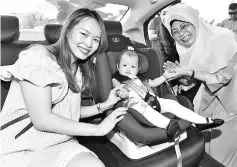  ??  ?? Fatimah poses with a baby in a child safety seat and her mother.