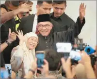  ?? ?? Malaysia’s newly appointed prime minister Anwar Ibrahim (C) with his wife Wan Azizah waves as they arrive ahead of his address at a gathering in Kuala Lumpur, Malaysia on Thursday.