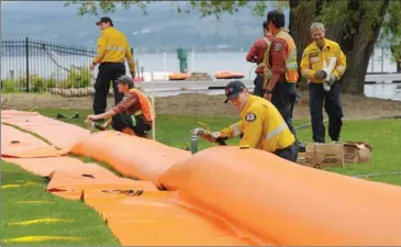  ?? GARY NYLANDER/The Daily Courier ?? BC Wildfire Service and West Kelowna Fire Rescue employees help set up aquadams at Pritchard Park in West Kelowna on Tuesday. Work crews continue to install flood protection against rising lake levels at various locations around the Central Okanagan.