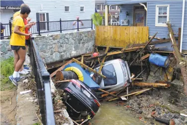  ?? David McFadden / Associated Press ?? Residents of Ellicott City, Md., examine cars tossed by flooding into a tributary of the Patapsco River.