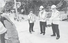  ??  ?? PUAS HATI: Lee (tengah) melihat pelan projek semasa meninjau tahap projek sistem perparitan konkrit bertutup yang telah 95 peratus siap di SJKC Chung Hua Tudan, baru-baru ini.