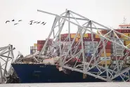  ?? ?? A cargo ship is stuck under part of the Francis Scott Key Bridge on Wednesday in Baltimore. (AP Photo/Steve Helber)