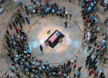  ?? J. SCOTT APPLEWHITE/AP PHOTO ?? Members of the public walk past the flag-draped casket bearing the remains of John McCain of Arizona, who was a member of Congress over four decades, in the U.S. Capitol rotunda in Washington on Friday. McCain was a six-term senator from Arizona, a former Republican nominee for president and a Navy pilot who served in Vietnam, where he endured five-and-a-half years as a prisoner of war. He died Aug. 25 from brain cancer at age 81.