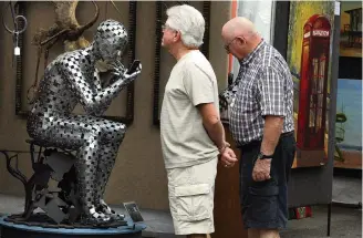  ?? MIKE STOCKER Sun Sentinel file ?? Frederic Largin and Jim Regan examine a sculpture by St. Augustine artist Seth Satterfiel­d at the Las Olas Art Fair. The fair was to be held this weekend but was canceled Wednesday.