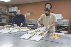  ?? JULIE DRAKE/ VALLEY PRESS ?? Volunteers Randy Pote (left) and Ken Miller prepare “to go” meals in the kitchen at Grace Resource Center on Friday.