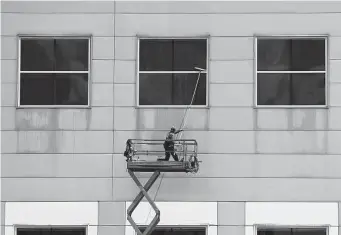  ?? Elizabeth Conley/Staff photograph­er ?? A worker cleans off the window on the second floor of NRG Center in July.