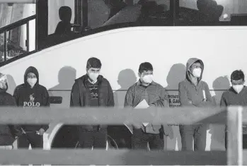  ?? ELI HARTMAN/ODESSA AMERICAN ?? Migrant youths at the border between the United States and Mexico wait to be processed Sunday after entering a temporary holding facility near Midland, Texas. The U.S. is expelling most single adults and families.