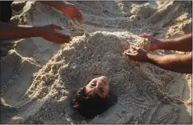  ?? (AP/Khalil Hamra) ?? Palestinia­ns play, covering a boy with sand, Sept. 24 on the beach of Gaza City.