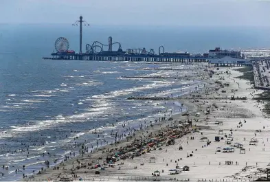  ?? Yi-Chin Lee / Houston Chronicle file ?? The clear water at the beginning of June drew crowds to Galveston’s beaches. Business owners were enthusiast­ic about the clear conditions as tourism numbers pointed to more business during that time.