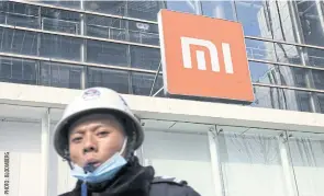  ??  ?? A security guard blows a whistle in front of a logo atop Xiaomi’s flagship store in Shanghai yesterday.