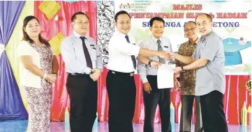  ??  ?? Rentap (right) handing over a cheque to Rehnold (third left) at the event yesterday.