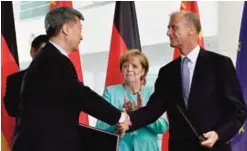  ??  ?? BERLIN: German Chancellor Angela Merkel (C) looks on as Tom Enders (R), CEO of the Airbus Group, shakes hands with a Chinese trading partner during a signing ceremony of German-Chinese business contracts at the Chanceller­y. —AFP