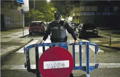 ?? CARLA GRAW ?? Un policía local coloca la valla de acceso prohibido en La Madrila.