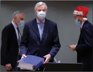  ??  ?? A colleague wears a Christmas hat as European Union chief negotiator Michel Barnier (center) carries a binder of the Brexit trade deal during a special meeting Friday at the European Council building in Brussels.
(AP/Olivier Hoslet)