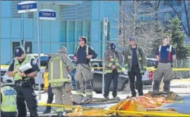  ?? REUTERS ?? ▪ Fire fighters stand near a covered body at a major intersecti­on in Toronto on Monday.