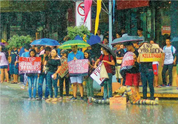  ?? ALDO NELBERT BANAYNAL ?? A handful of students stay undeterred by the downpour in Cebu City yesterday as they protest government's action on controvers­ial issues, including the ongoing war against illegal drugs.