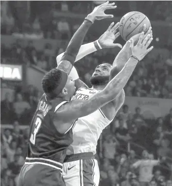  ??  ?? Los Angeles Lakers forward LeBron James, right, shoots against Denver Nuggets forward Torrey Craig defending during the first half of an NBA basketball game in Los Angeles. (ASSOCIATED