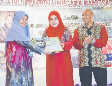  ??  ?? Norsyamsya­fikhoh (left) receives the Ikon Guru award from Rakayah while Hassan (right) applauds.