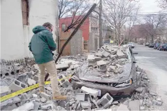  ??  ?? An insurance company employee checks the damage to a car after a partially burnt building collapsed due to strong winds in Northeast Washington. — AFP