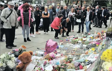  ?? PICTURE: RUI VIEIRA / AP ?? SHARED GRIEF: Members of the public look at tributes in Albert Square in central Manchester yesterday after an explosion at an Ariana Grande concert on Monday night killed 22 fans.