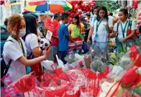  ?? AFP ?? Customers browse for gifts and flowers for sale at a flower market on Valentine’s Day in Manila on Tuesday. —