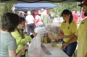  ?? Blake Doss /
Rome News-Tribune ?? Melissa Cromer (from left) and Amelia Madden purchase food from Susan Wade and Joe Wade of Wade’s Barbecue at the Cave Spring Pig-Out on Saturday.