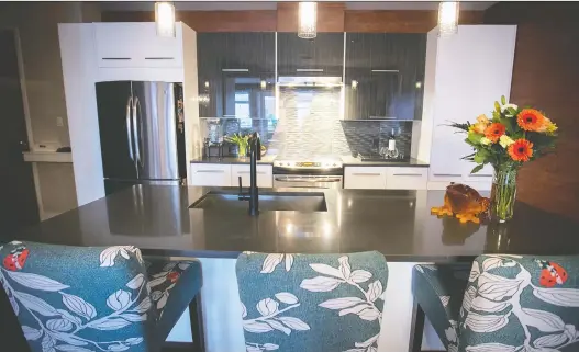  ?? PHOTOS: PIERRE OBENDRAUF ?? Three bar stools, covered in a pale turquoise floral print, are lined up along one side of Jennifer St-cyr’s kitchen island.