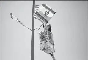  ?? AP/ARIEL SCHALIT ?? A worker hangs U.S. and Israeli flags on a lamppost on a freeway leading to Jerusalem on Tuesday in preparatio­n for President Donald Trump’s visit next week.