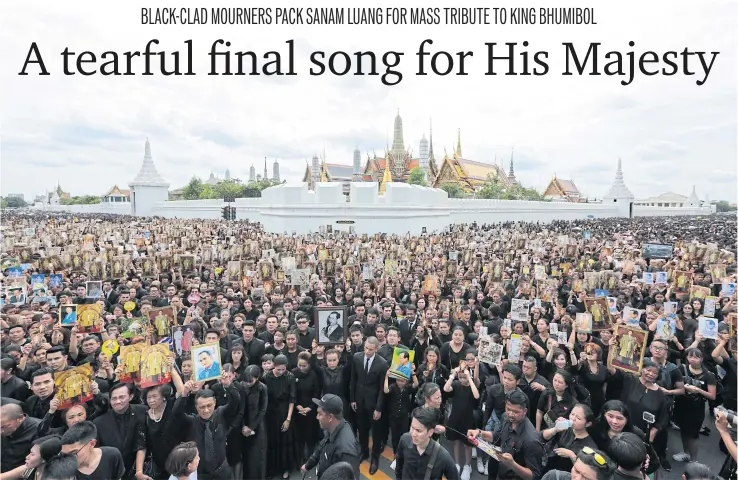 ?? PHOTO: PATIPAT JANTHONG ?? UNITED IN GRIEF: Mourners wave pictures of His Majesty the King before singing the Royal Anthem for the last time at Sanam Luang yesterday in a mass tribute organised by filmmaker MC Chatrichal­erm Yukol.