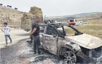  ?? — Reuters ?? Palestinia­ns check a car burned by Israeli settlers near Ramallah in the Israeli-occupied West Bank.