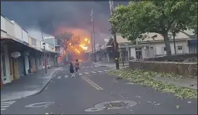  ?? ALAN DICKAR VIA AP ?? People watch as smoke and flames fill the air from raging wildfires Tuesday night on Front Street in downtown Lahaina, Hawaii, on the island of Maui. Maui officials say wildfire in the historic town has burned parts of one of the most popular tourist areas in Hawaii and left at least six people dead.