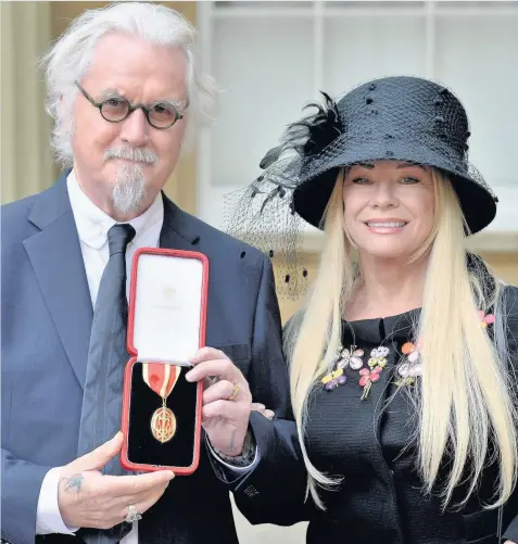  ??  ?? > Sir Billy Connolly with his wife, Pamela Stephenson, after being knighted by the Duke of Cambridge at Buckingham Palace yesterday